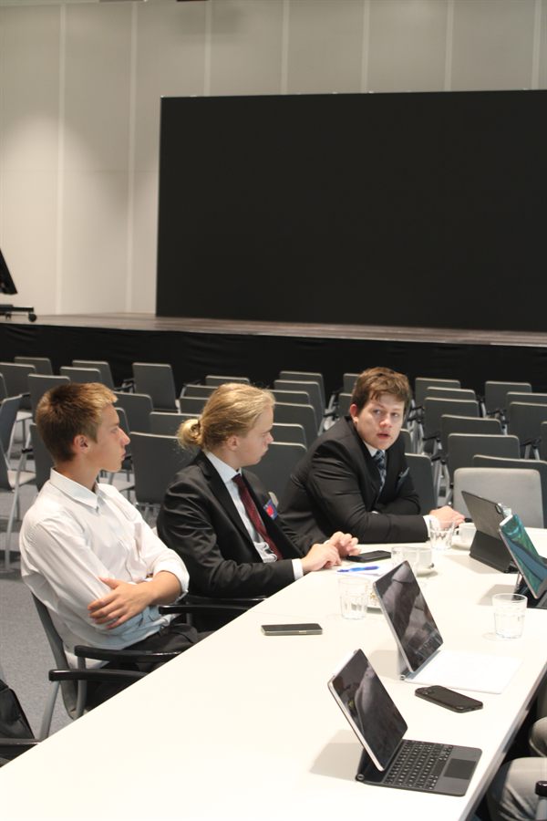 Delegates drafting at laptops around a committee table.